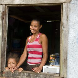 madre con diastema gap-tooth e figlia davanti a una casa di legno nella povertà di Big Corn Island Nicaragua, America Centrale